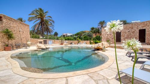 a pool in a patio with chairs and a palm tree at Residence Il Corallo - Guitgia in Lampedusa