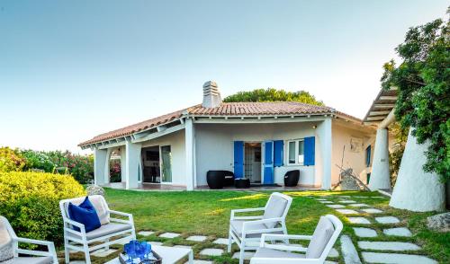 a house with white chairs in the yard at Villa Miriam - Klodge in Olbia