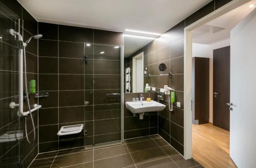 a bathroom with a sink and a shower at JUFA Hotel Hamburg HafenCity in Hamburg