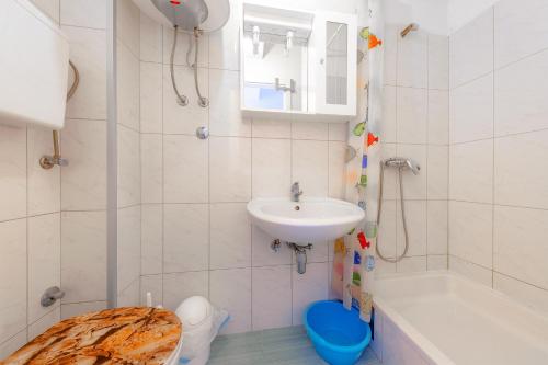 uma casa de banho com um lavatório, um WC e um chuveiro em Eco-Apartments with nice garden em Baska Voda