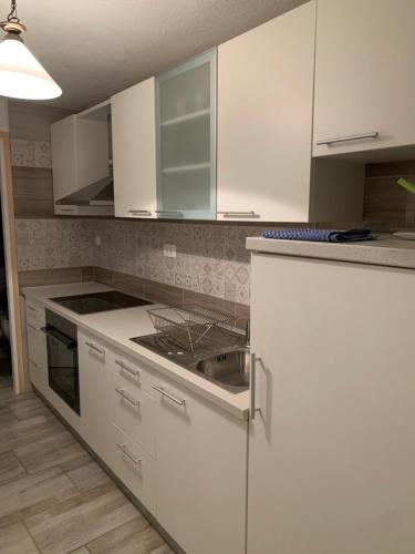 eine Küche mit weißen Schränken und einem Waschbecken in der Unterkunft Apartman Annamaria in Cres
