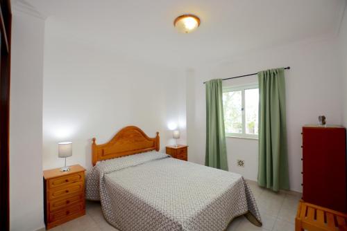 a bedroom with a bed and a window with green curtains at Casa Nau B in Armação de Pêra