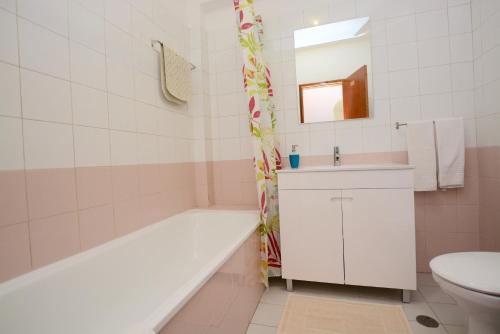 een badkamer met een bad, een wastafel en een toilet bij Casa Nau B in Armação de Pêra