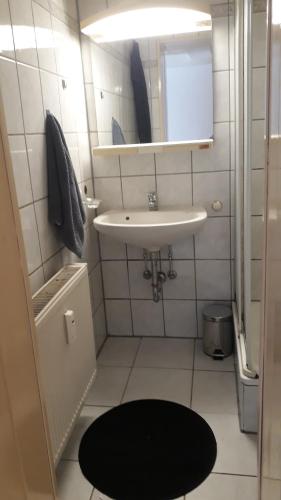 La salle de bains blanche est pourvue d'un lavabo et d'un miroir. dans l'établissement Roter Backstein Apartment 1, à Mayence