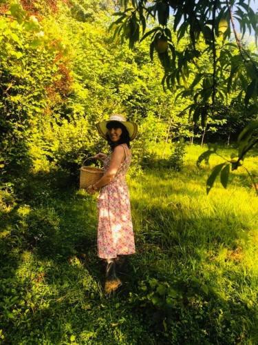 a woman standing in the grass holding a basket at Martv'Elle Boutique Guesthouse in Martvili