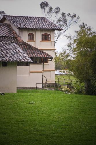 a house with a green field in front of it at Hacienda San Isidro Trails & Experiences in Cotacachi