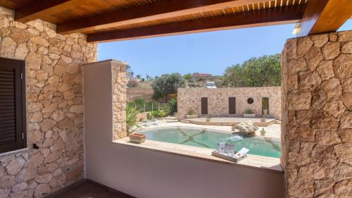 - une vue extérieure sur une maison en pierre avec une piscine dans l'établissement Residence Il Corallo - Guitgia, à Lampedusa