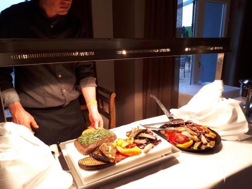a man standing next to a table with two plates of food at Heitlinger Hof in Tiefenbach