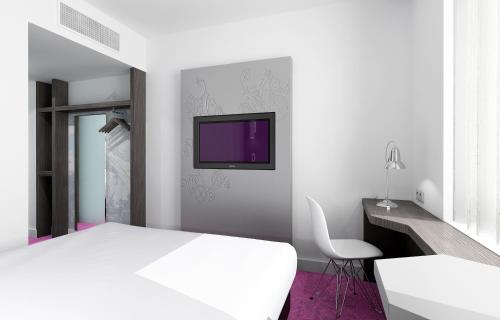 een slaapkamer met een wit bed en een tv aan de muur bij VISIONAPARTMENTS Geneva Gare in Genève