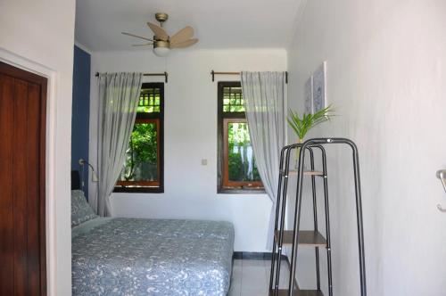 a bedroom with a bed and a fan and two windows at Guesthouse The 4 Fish in Manado