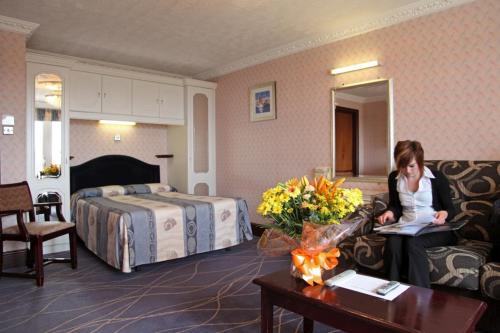 a woman sitting on a couch in a hotel room at The Devoncourt Resort in Exmouth