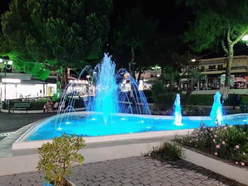 una fontana con acqua blu in un parco di notte di Mariza Apartments -studios a Hanioti