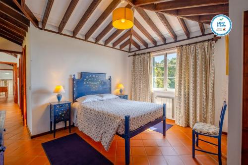 sypialnia z niebieskim łóżkiem i oknem w obiekcie Casas do Termo w mieście Lagoa