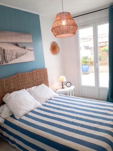- une chambre avec un lit rayé bleu et blanc et une fenêtre dans l'établissement Les portes du soleil, à Les Sables-dʼOlonne