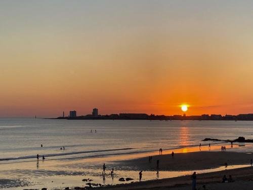 a group of people on the beach at sunset at Les portes du soleil in Les Sables-d'Olonne