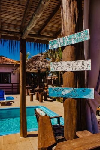 a resort with signs on a pole with a pool at Pousada Mares do Santinho in Florianópolis