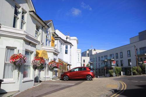 a red car parked on a street next to buildings at Dolphins Hotel in Bournemouth