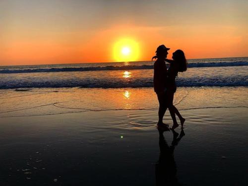 a couple walking on the beach at sunset at Seaside Garden Ecolodge Mompiche in Mompiche