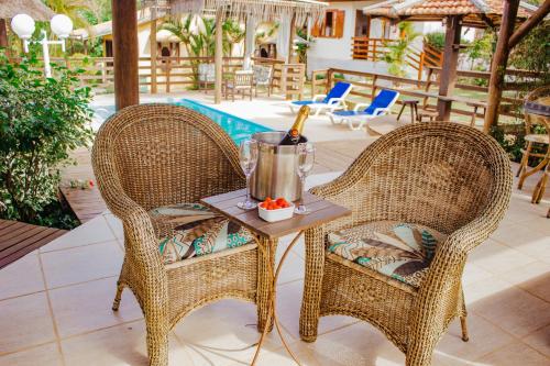 two wicker chairs and a table with a bottle of champagne at Pousada Mares do Santinho in Florianópolis