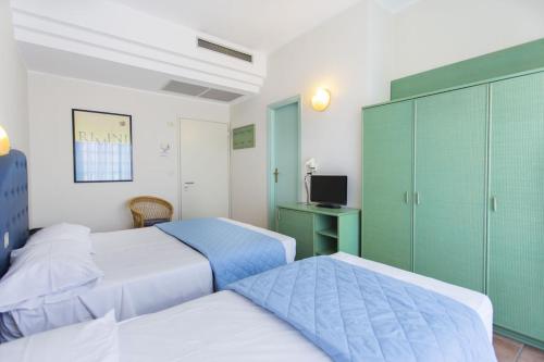 Habitación de hotel con 2 camas y escritorio en Bellariva Feeling Hotel, en Rímini