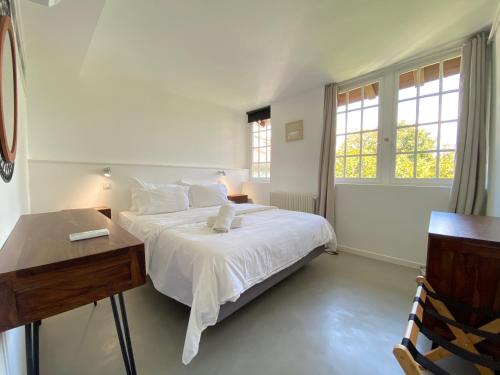 biała sypialnia z łóżkiem, biurkiem i oknami w obiekcie Boutique Hôtel Un Appart en Ville w Bajonnie