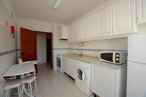 a kitchen with white cabinets and a washer and dryer at Casa Canoa B in Armação de Pêra