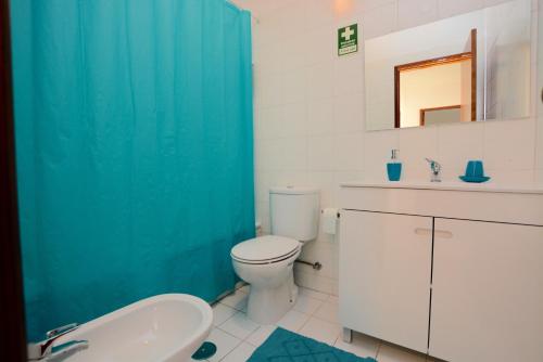 baño con aseo blanco y cortina de ducha azul en Casa Canoa B, en Armação de Pêra