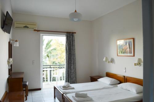 um quarto de hotel com duas camas e uma janela em Paradise Beach Apartments em Argasi