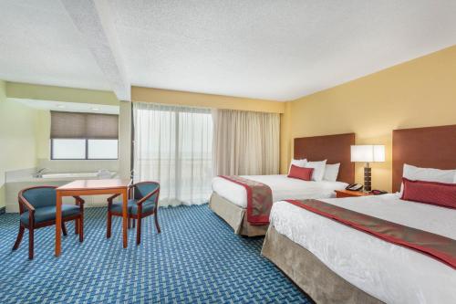 a hotel room with two beds and a desk at Ramada Plaza by Wyndham Virginia Beach Oceanfront in Virginia Beach