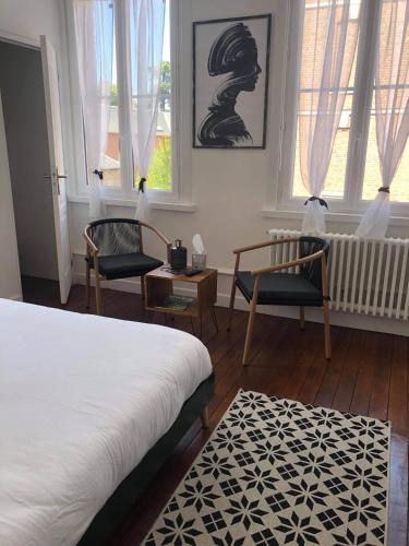 a bedroom with two beds and two chairs and windows at Ginkgo Maison d'hôtes in Amiens