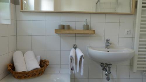 a white bathroom with a sink and a basket of towels at FEWO am Markt in Neustadt in Sachsen