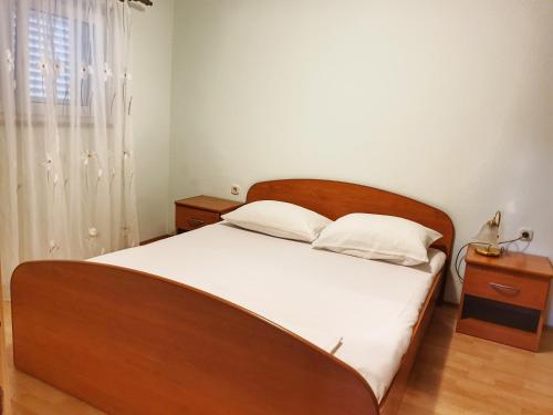 a bedroom with a large wooden bed with white sheets at BetaNovalja in Novalja