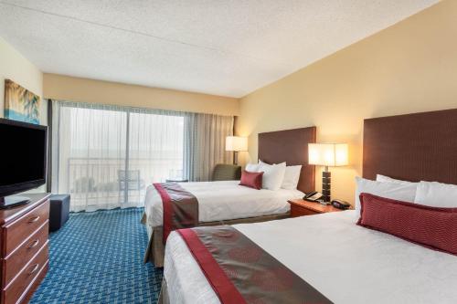 a hotel room with two beds and a flat screen tv at Ramada Plaza by Wyndham Virginia Beach Oceanfront in Virginia Beach