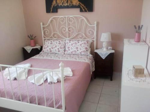 a bedroom with a pink and white bed with two tables at SIAS HOUSE in Lixouri