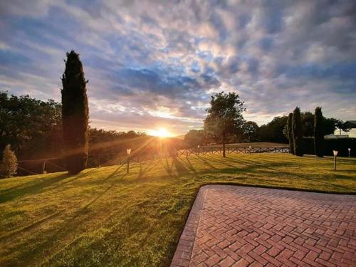 un coucher de soleil dans un champ avec une passerelle en briques dans l'établissement Agriturismo Podere Del Lepre, à San Quirico