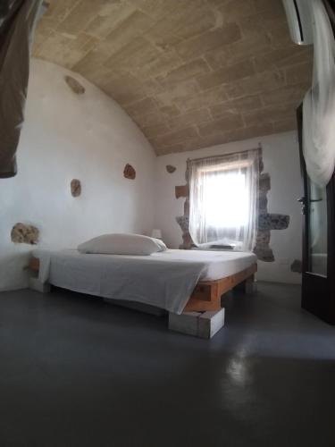 1 dormitorio con cama y ventana en La Torre di Merlino, en Patù