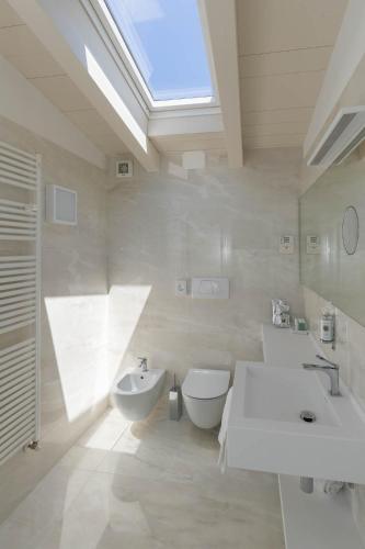 a bathroom with two sinks and a toilet and a skylight at Hotel Vega in Malcesine