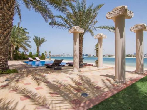 a resort yard with a pool and palm trees at Palm's Largest Beachfront Estate in Dubai