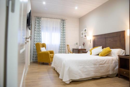 a bedroom with a large bed and a yellow chair at Azafrán Consuegra in Consuegra