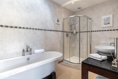 y baño con bañera, ducha y lavamanos. en Dormie Cottage, lovely bright and spacious bungalow with wood fire en Ballater