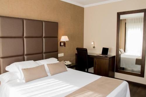 a bedroom with a bed and a desk with a computer at Hotel A Queimada in Parada