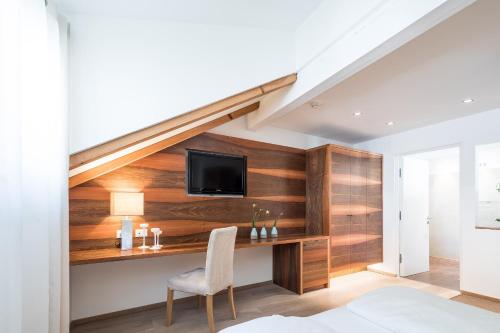 a bedroom with a wooden wall with a desk and a tv at Boutique Hotel Zum Rosenbaum in Nalles