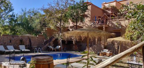 a house with a swimming pool with an umbrella at Riad Des Vieilles Charrues in Boumalne