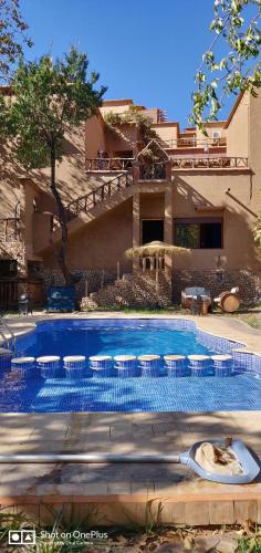 a swimming pool in front of a house at Riad Des Vieilles Charrues in Boumalne Dades