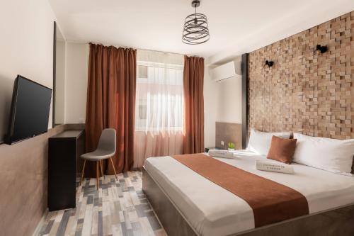 ein Hotelzimmer mit einem großen Bett und einem TV in der Unterkunft ОРФЕЕВИТЕ ПЕСНИ in Dewin