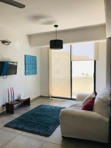 a living room with a couch and a large window at Cómodo y lindo depa con Alberca in Puerto Vallarta