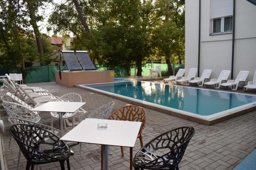 un patio con mesas y sillas junto a una piscina en Lido Riviéra, Relux Apartman Balatonlelle, en Balatonlelle