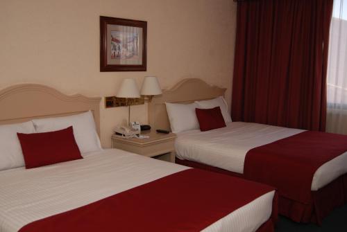 two beds in a hotel room with red curtains at Quality Inn Aguascalientes in Aguascalientes