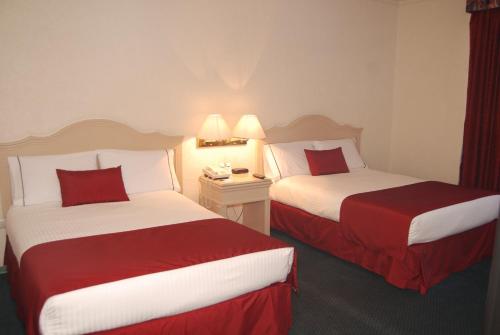 two beds in a hotel room with red and white at Quality Inn Aguascalientes in Aguascalientes