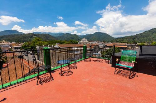 a group of chairs and tables on a balcony with mountains at Hotel La Sin Ventura in Antigua Guatemala